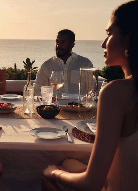 Sunset dinner by the sea at eau palm beach, with friends gathered around a warmly lit outdoor table.