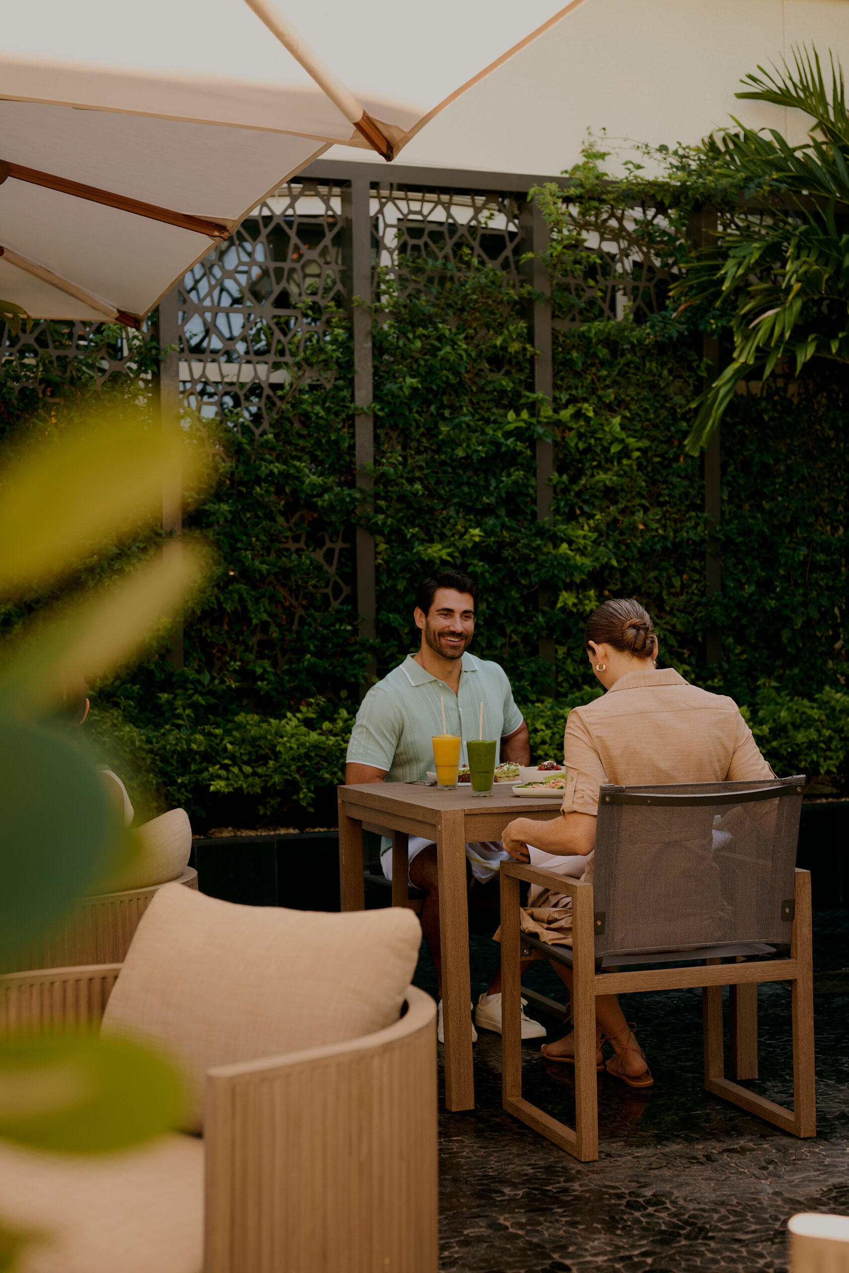 Couple enjoying drinks and meal at outdoor garden patio table under umbrella