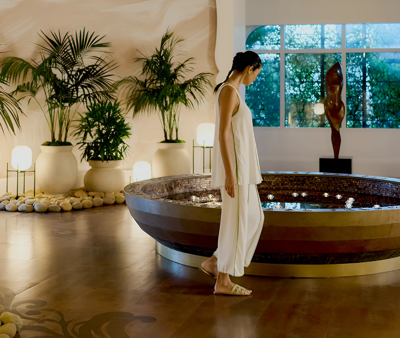 Calming indoor space with a circular water feature, soft lighting and lush greenery