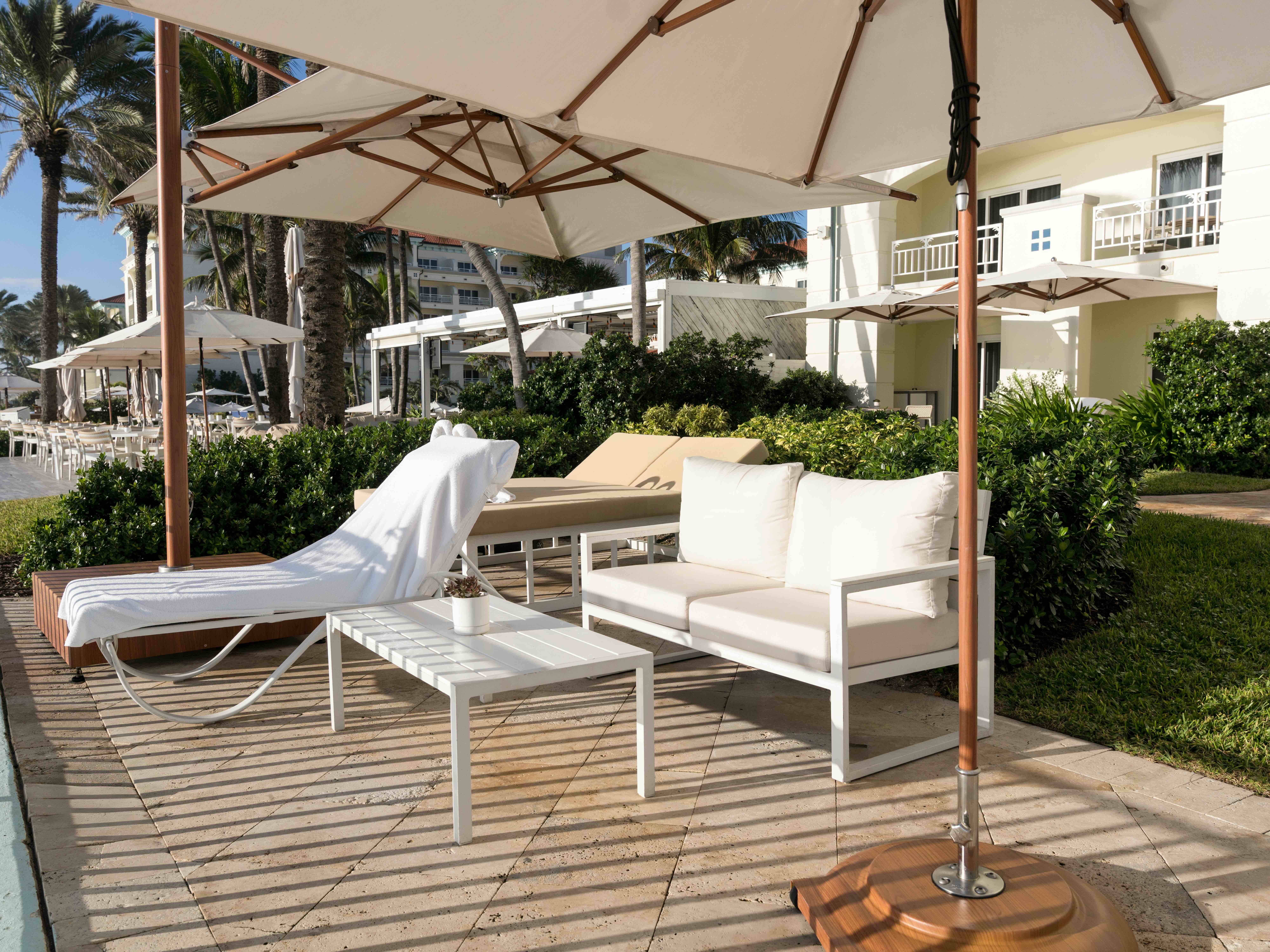Luxury poolside lounge chairs and sofa under umbrellas at tropical resort