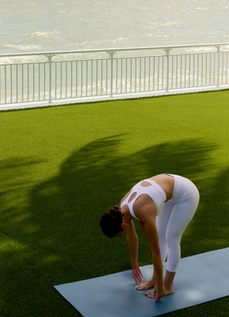 Woman practicing yoga on mat outdoors near oceanfront railing