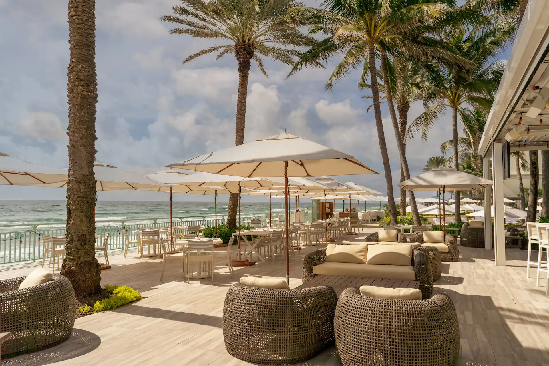 Breeze ocean kitchen 6 Oceanfront lounge at breeze ocean kitchen with white umbrellas, palm trees and relaxed coastal seating at eau palm beach