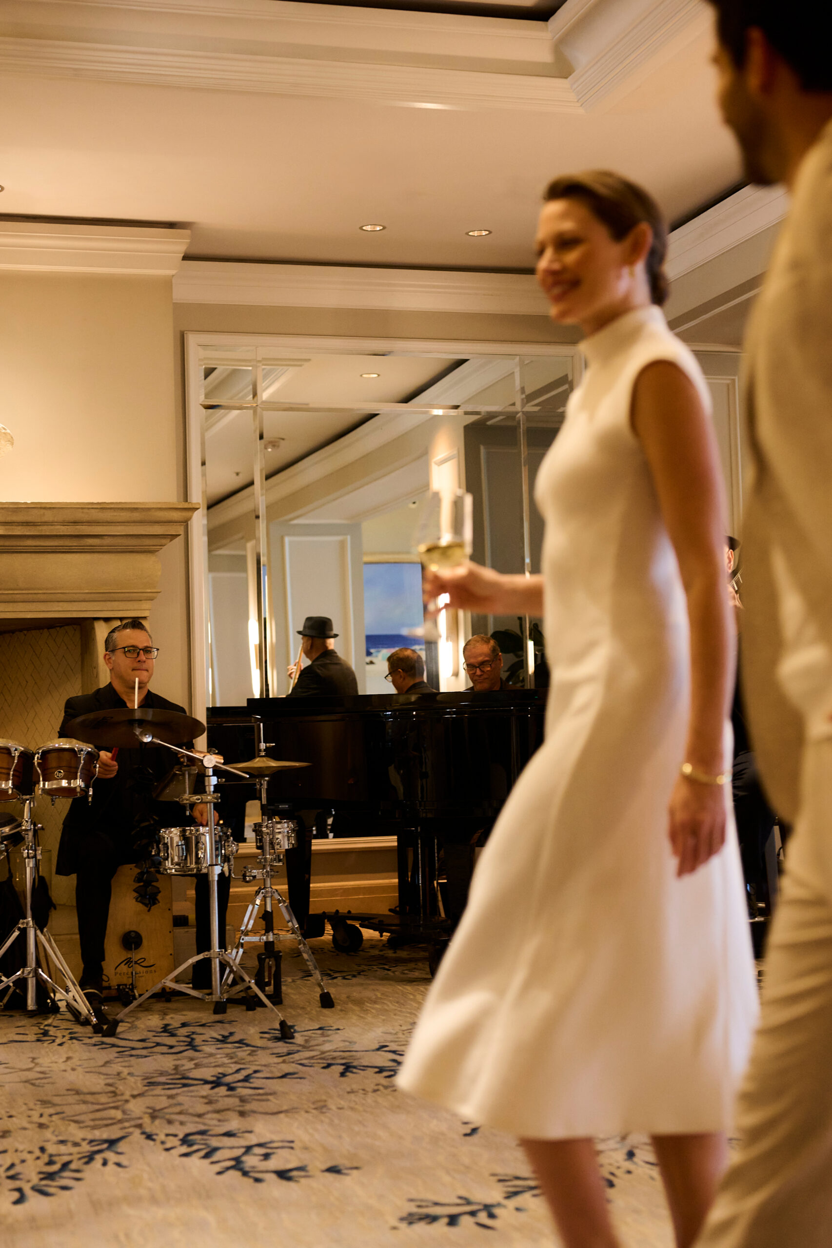 Woman in white dress holding a wine glass while live musicians play in an elegant lounge