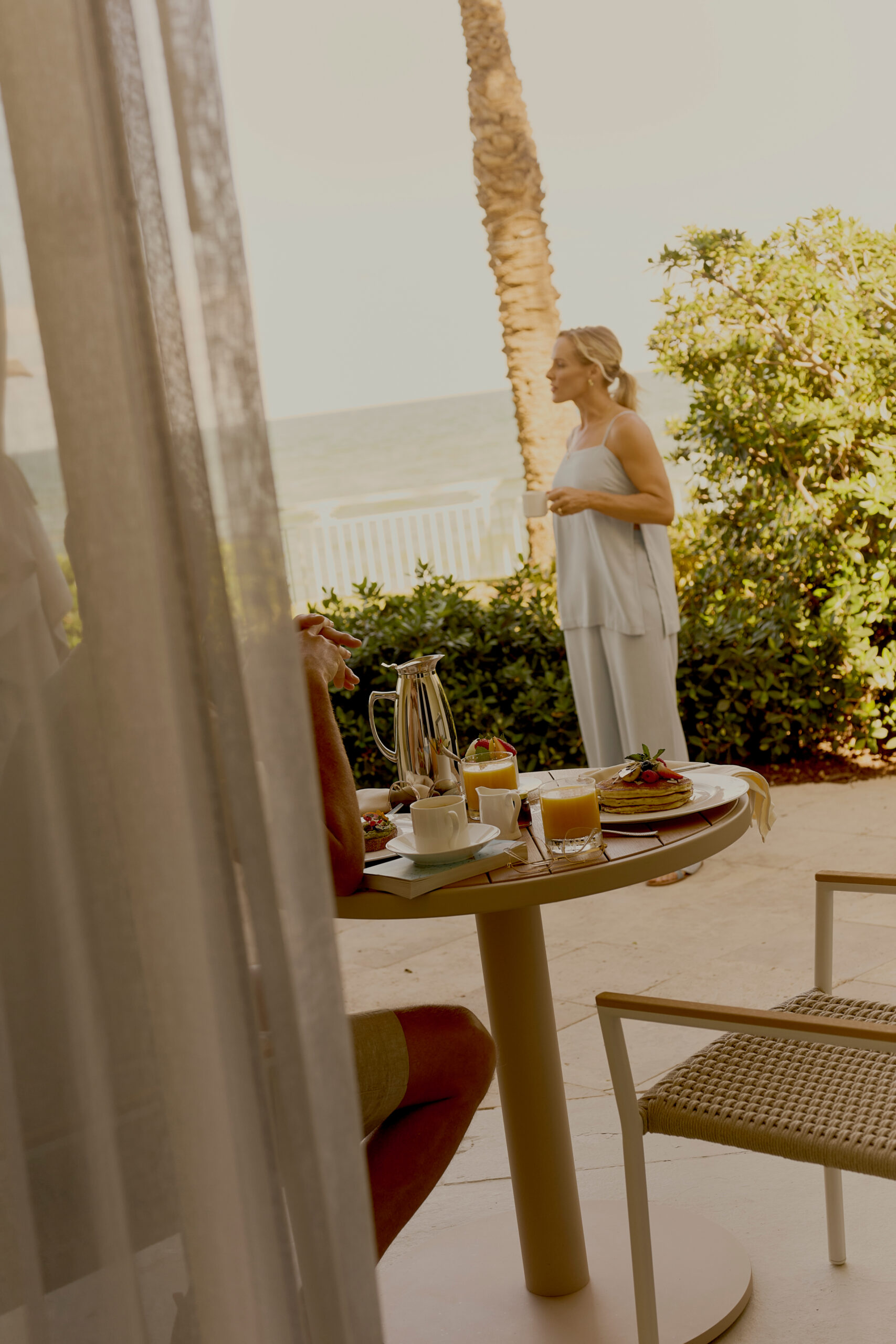 Couple enjoying breakfast with coffee and pancakes on a sunny beachfront patio