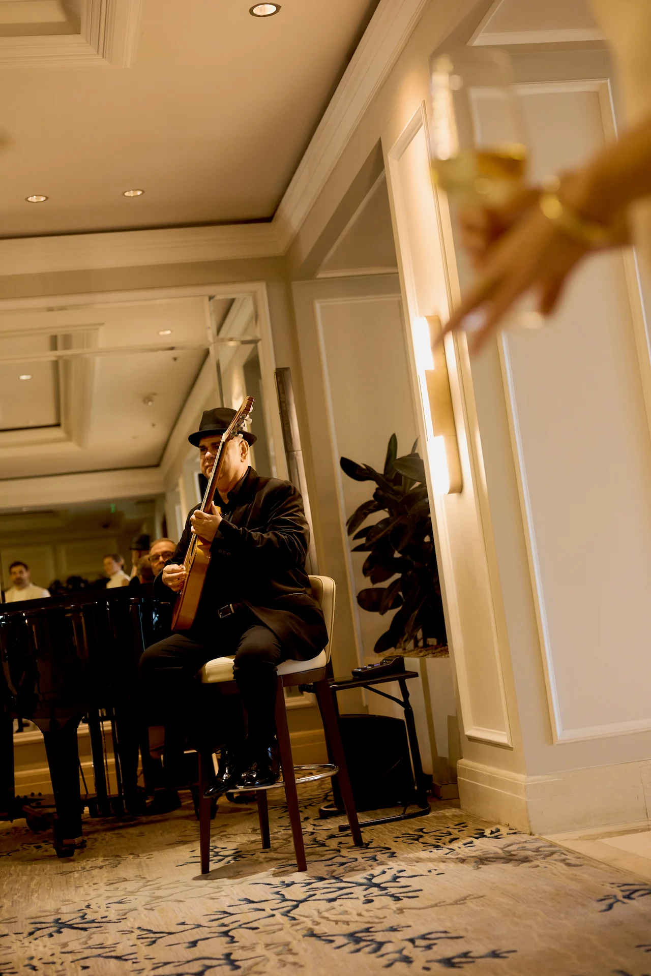 Live guitar performance in an elegant lounge, with a champagne glass in the foreground and guests reflected in the mirror