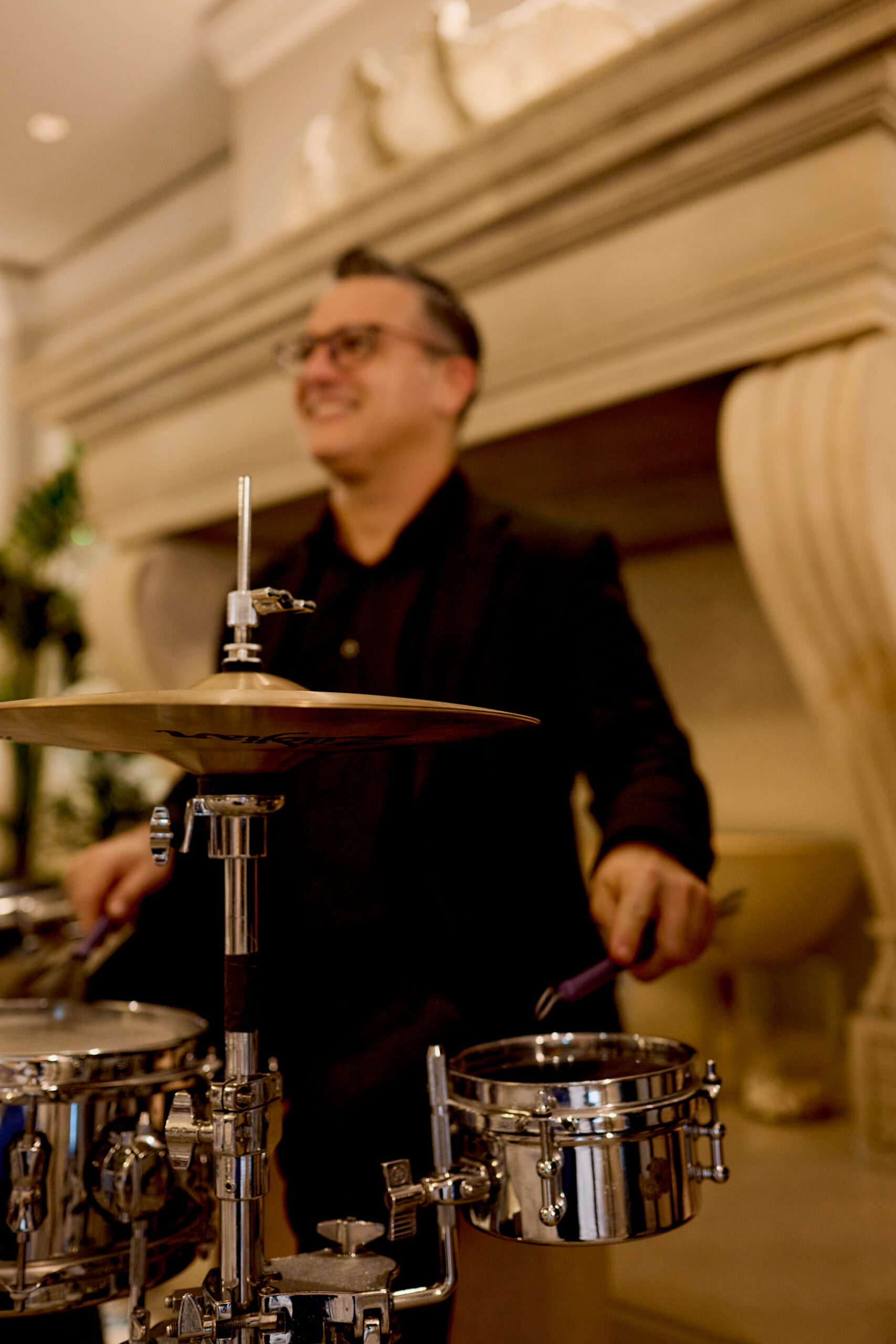 Smiling musician playing drum set with cymbal in elegant indoor venue