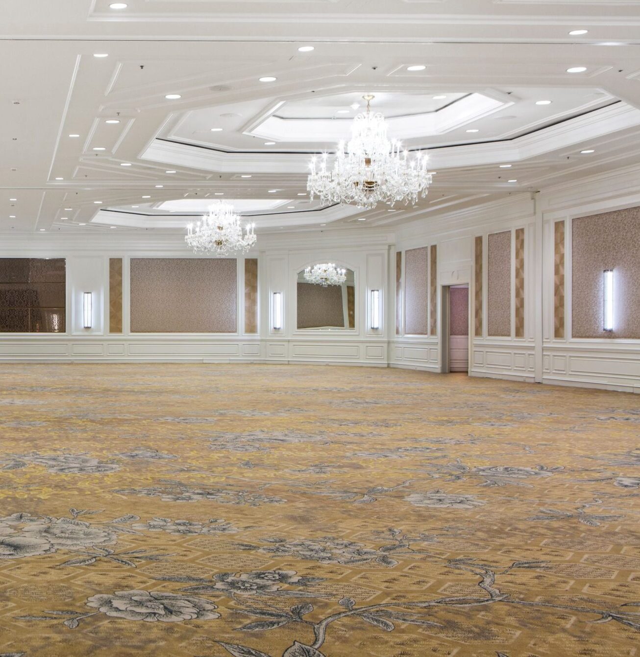 Spacious elegant ballroom with chandeliers, ornate ceiling, and patterned carpet