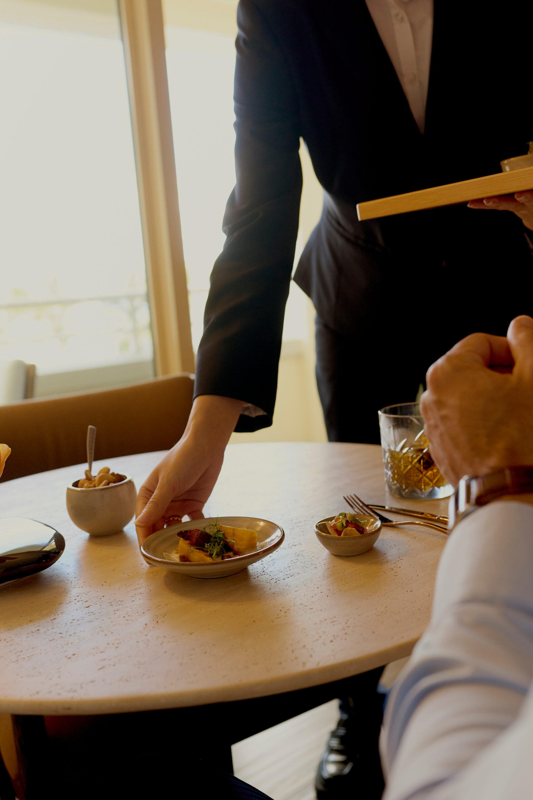 Server placing gourmet dish on table for guest in elegant restaurant setting