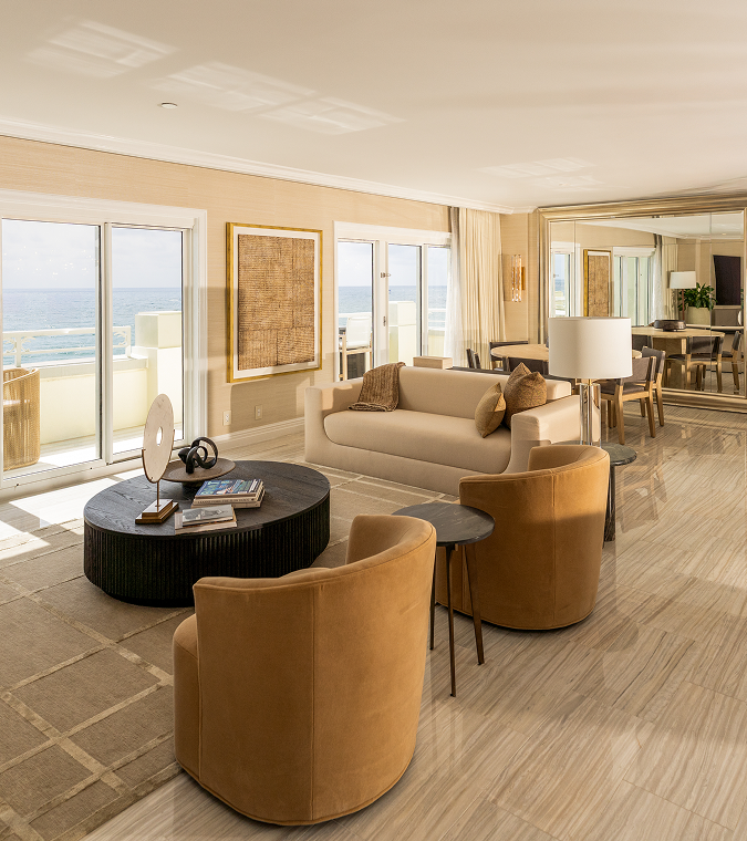 Bright oceanview living room with modern furniture, balcony doors, and warm neutral tones