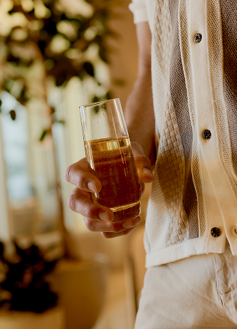 Person holding a glass of iced tea in a warmly lit indoor setting
