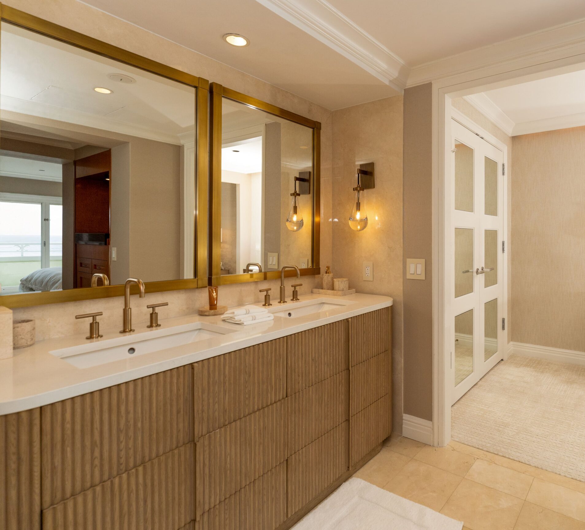 Elegant bathroom with double vanity, gold framed mirrors, and warm lighting