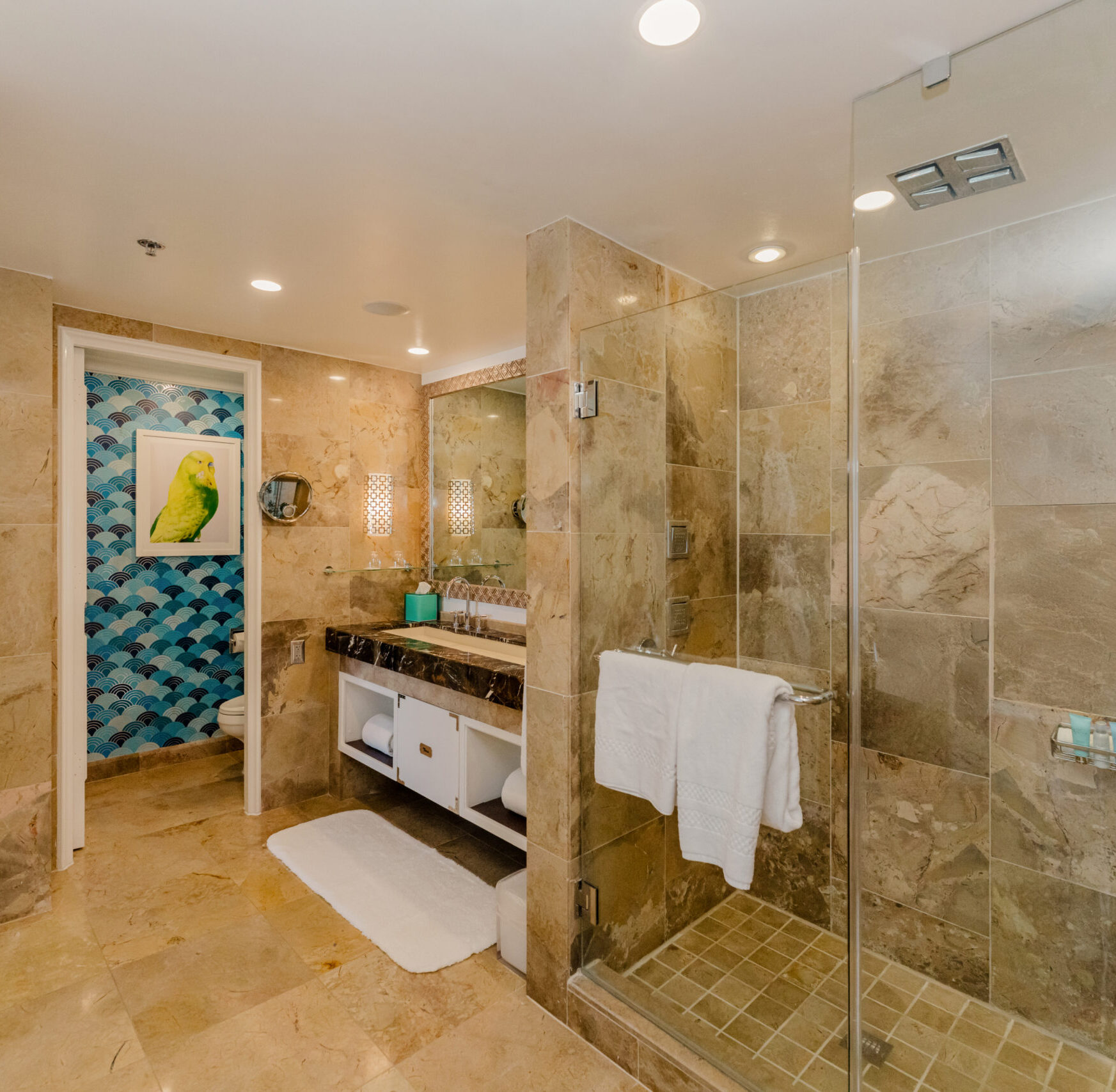 Spacious marble bathroom with glass shower, vanity, and patterned accent wall artwork