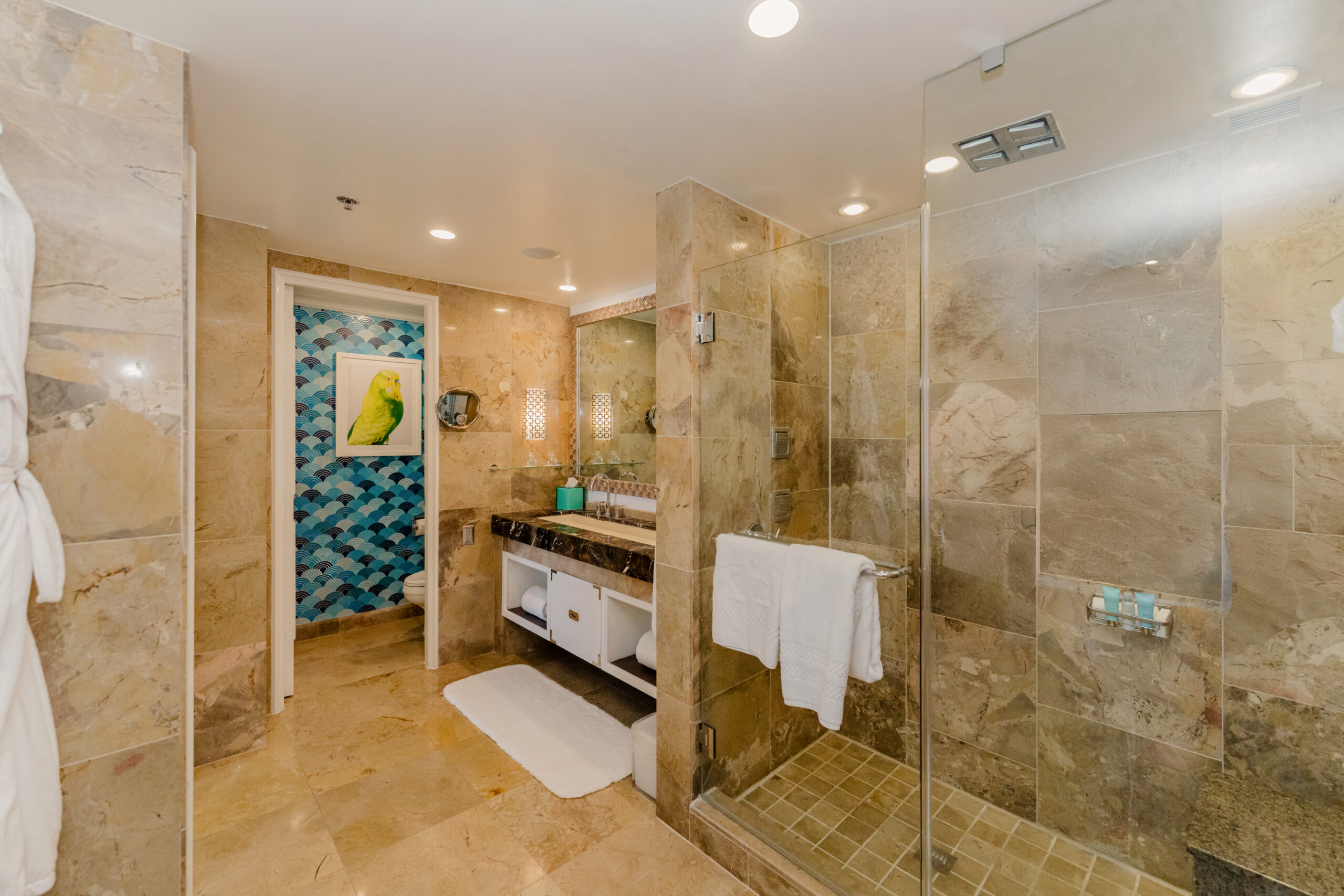 Spacious marble bathroom with glass shower, vanity, and patterned accent wall artwork