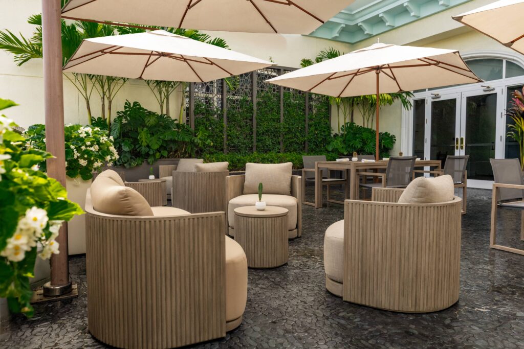 Outdoor courtyard seating area with umbrellas, cushioned chairs, and lush greenery