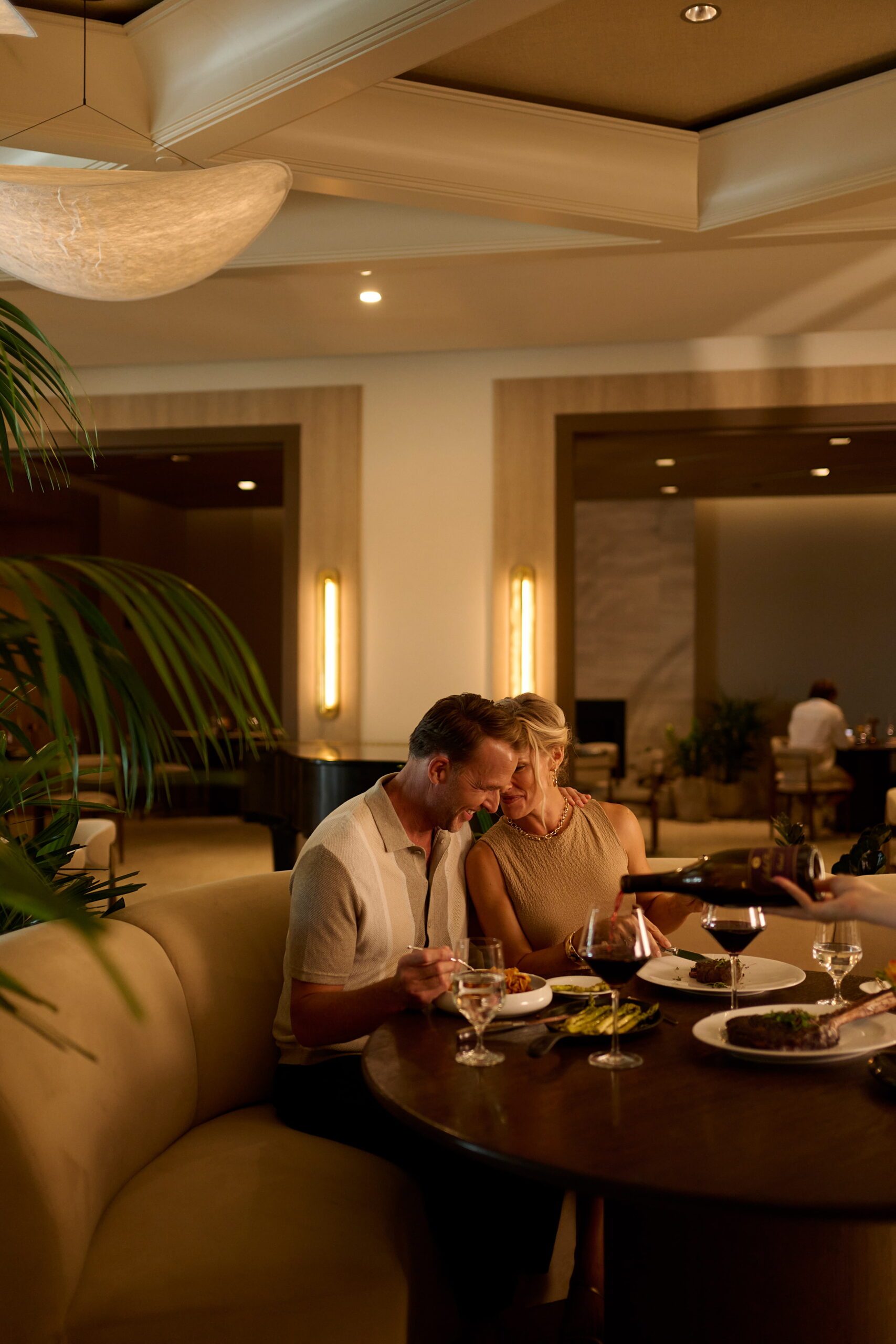 Couple enjoying romantic dinner with steak and wine in elegant restaurant setting