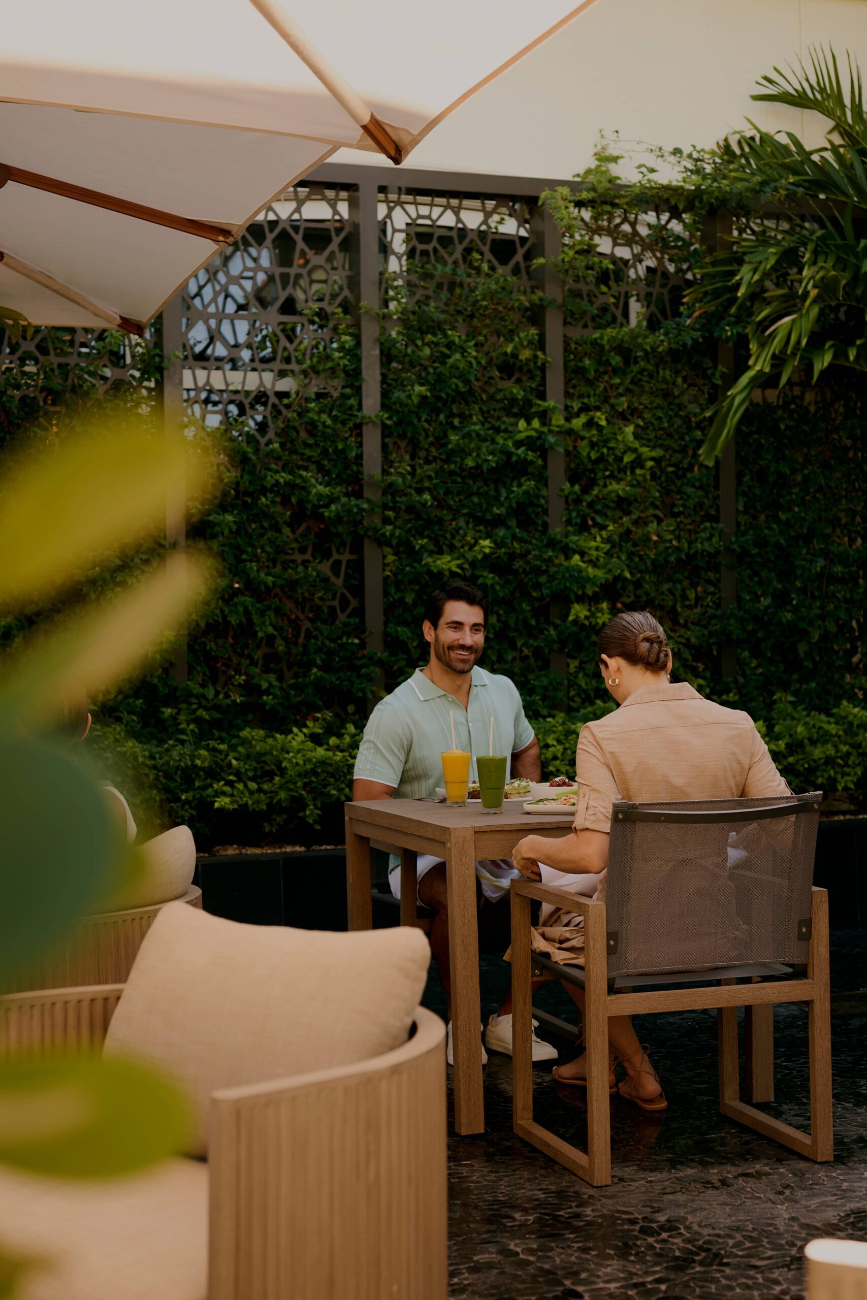 Couple enjoying drinks and meal at outdoor garden restaurant patio