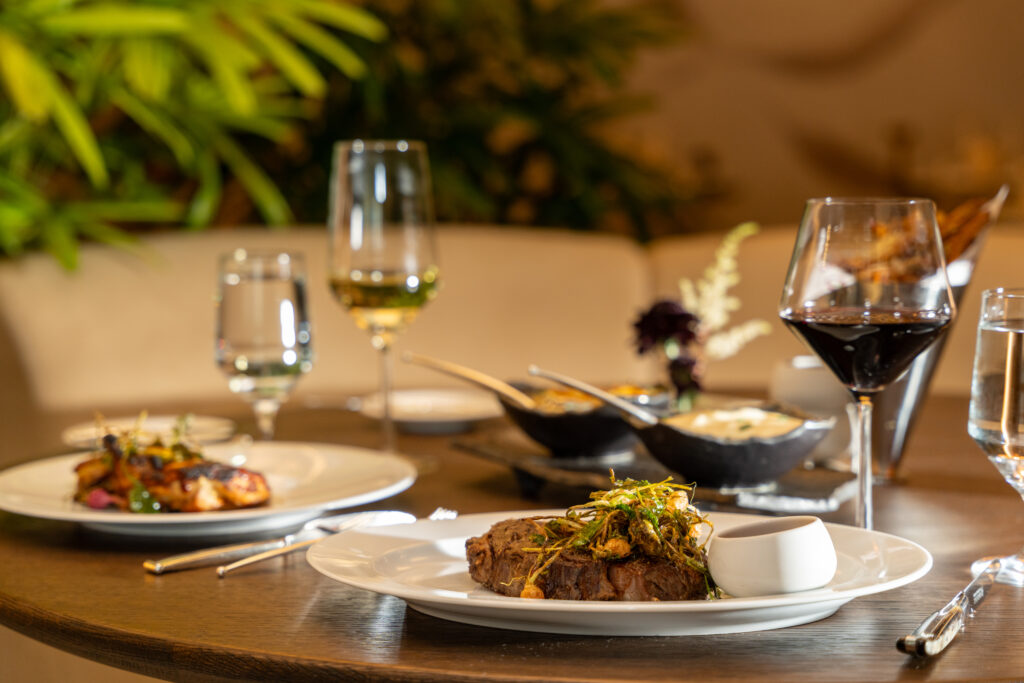 Gourmet steak dinner with wine and side dishes on elegant restaurant table