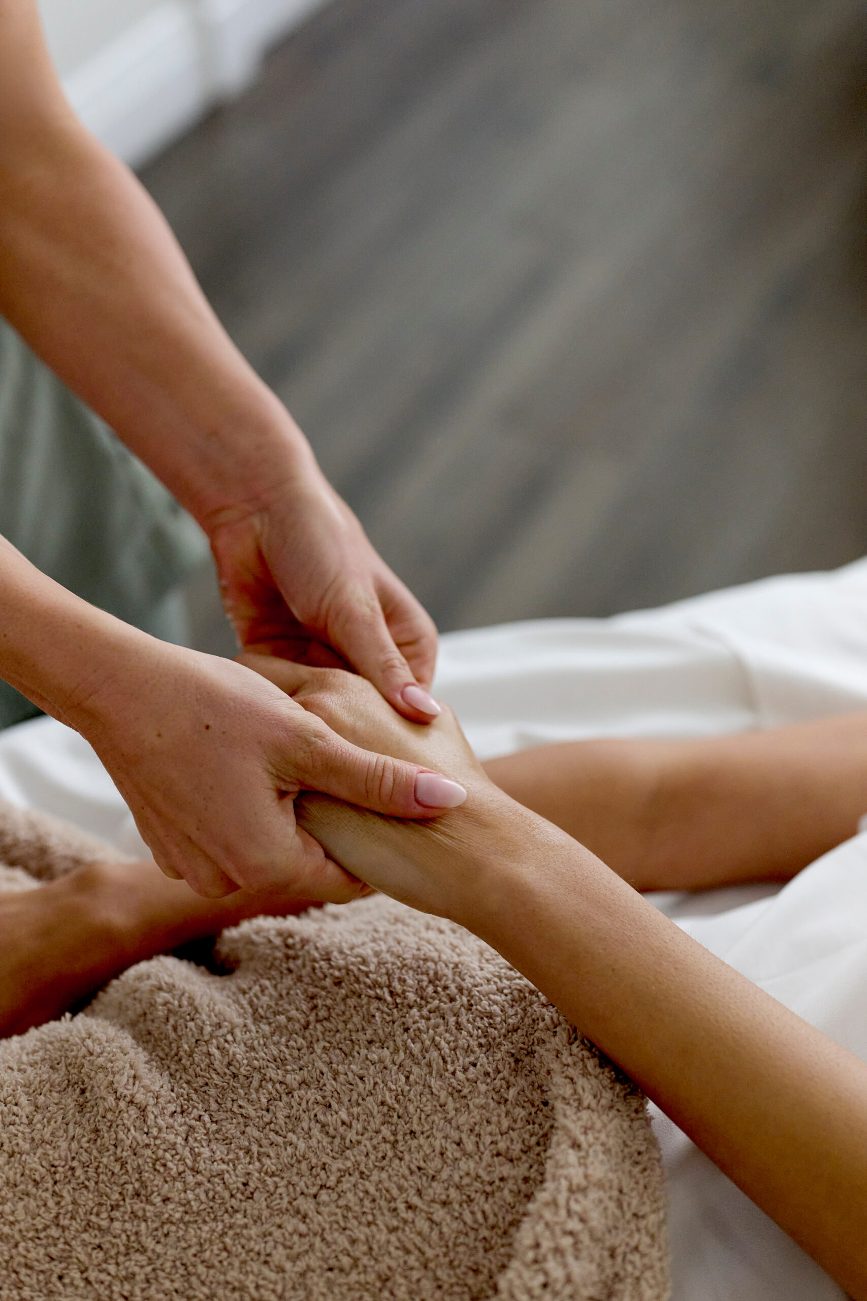 Therapist giving relaxing hand massage to client lying on spa table with towel