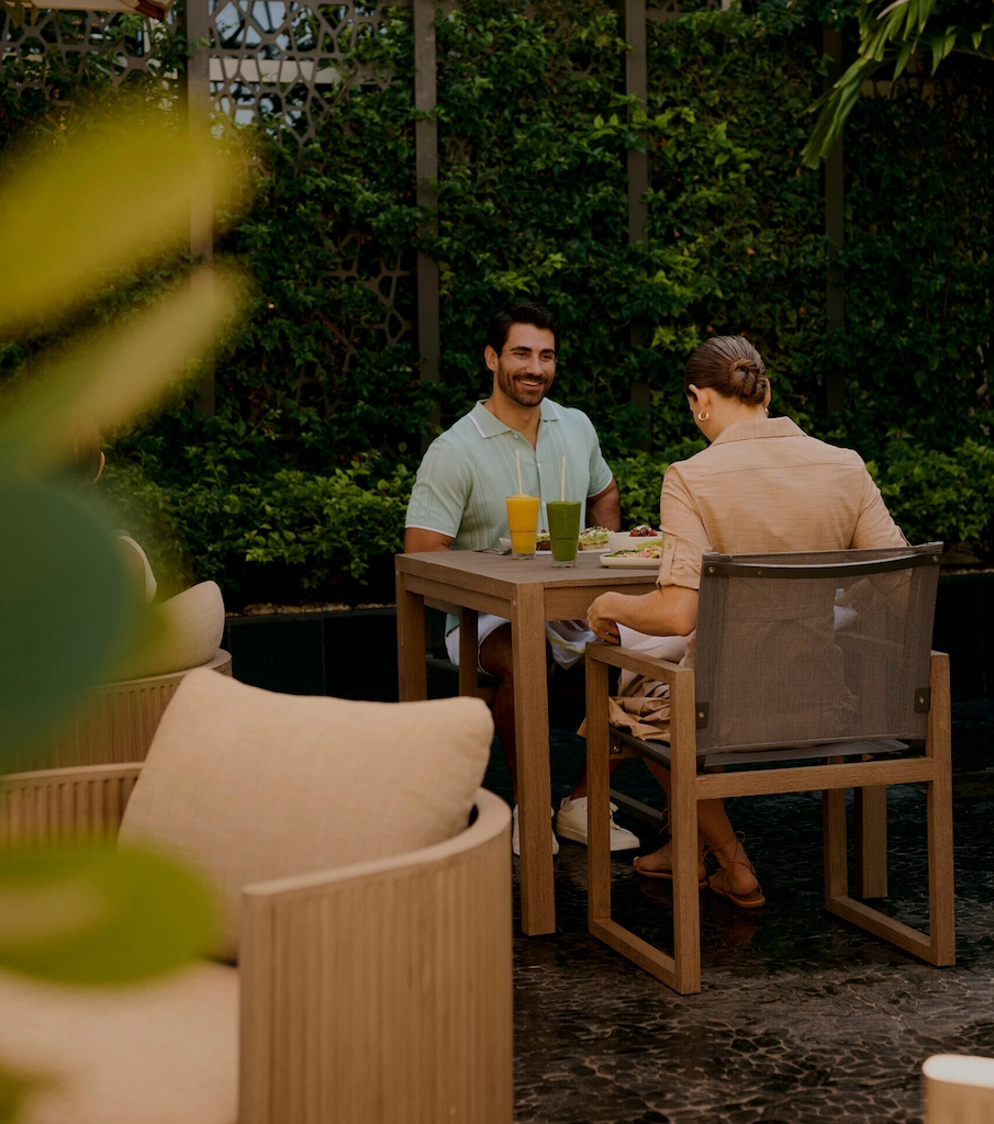 Couple enjoying drinks and meal at outdoor garden patio table under umbrella
