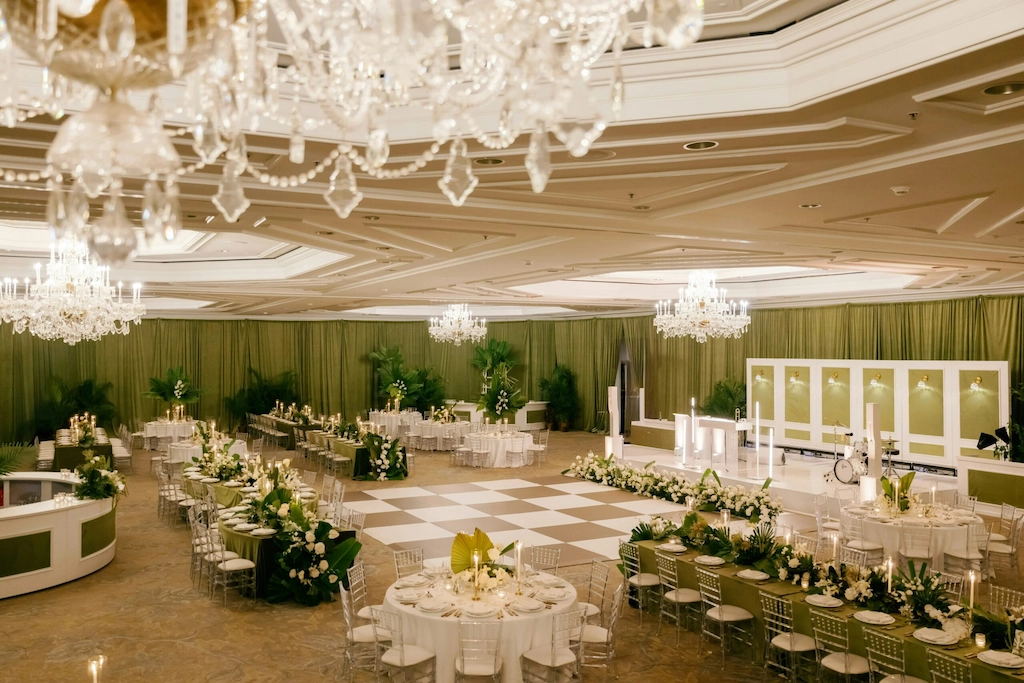 Luxurious ballroom set for wedding reception with chandeliers, floral decor, and dance floor