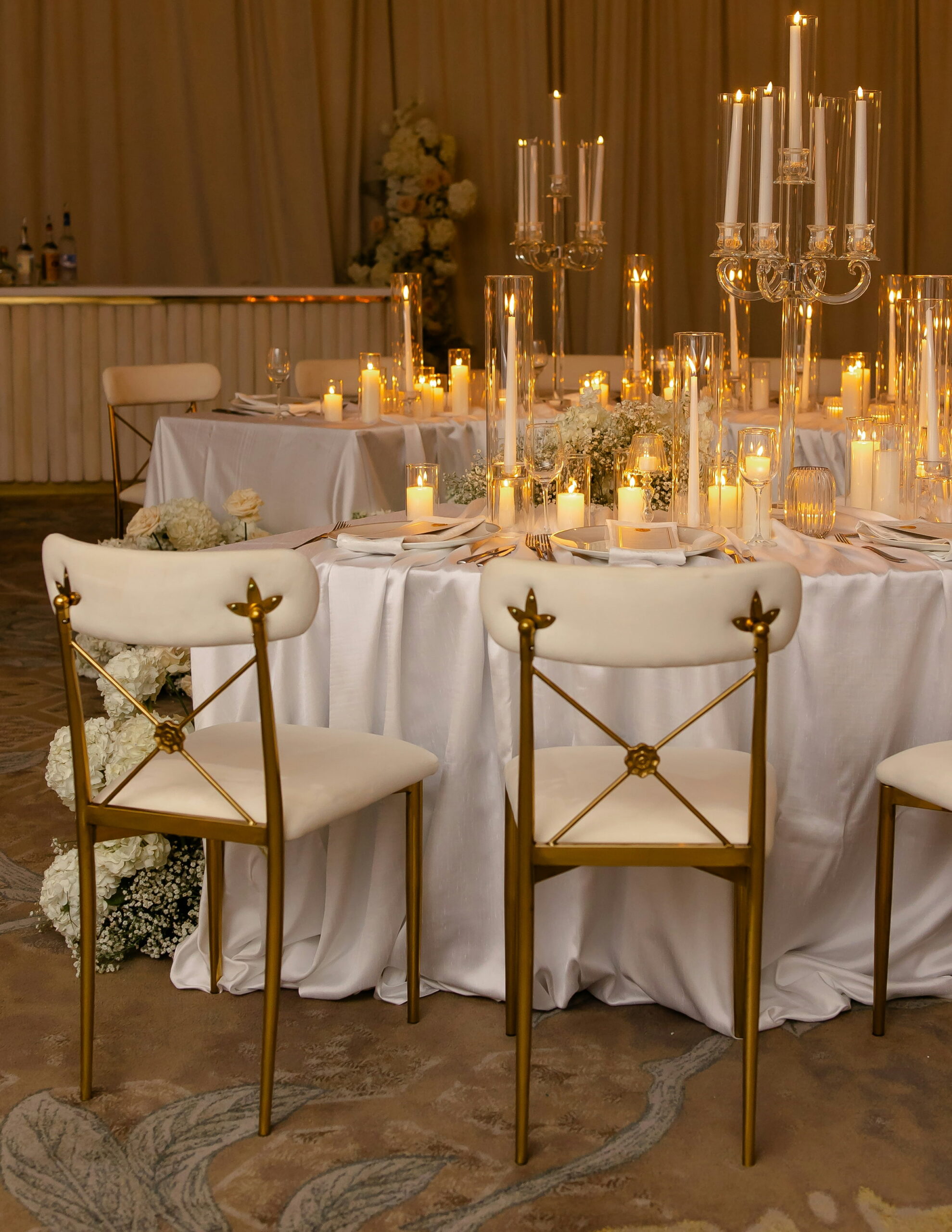 Elegant candlelit reception table with gold chairs and white floral decor