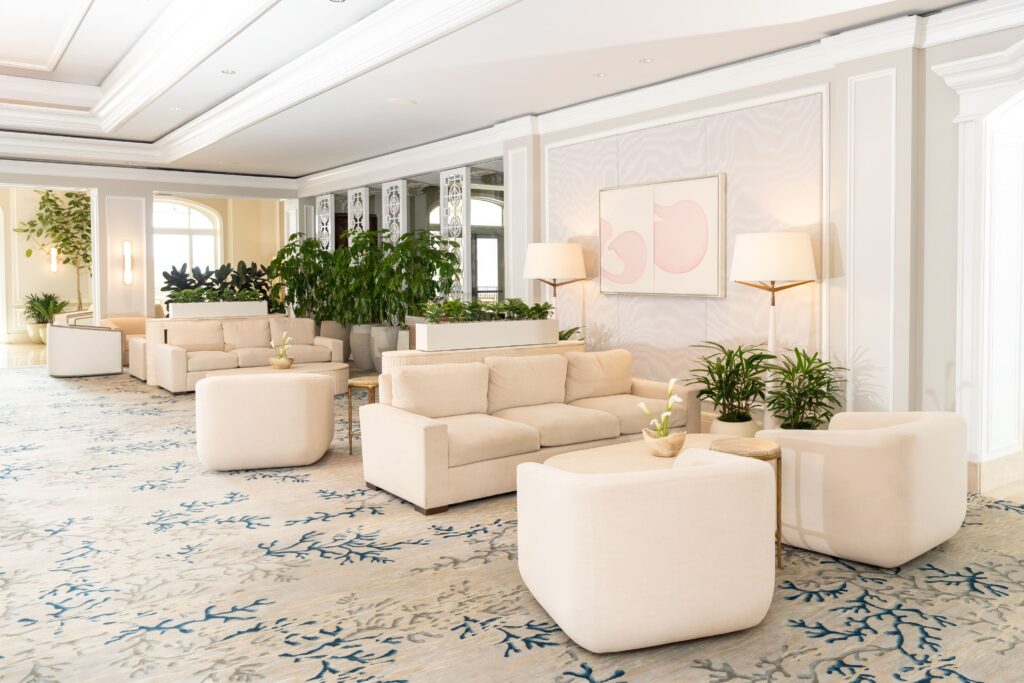 Elegant hotel lounge with cream sofas, lush plants, and soft lighting