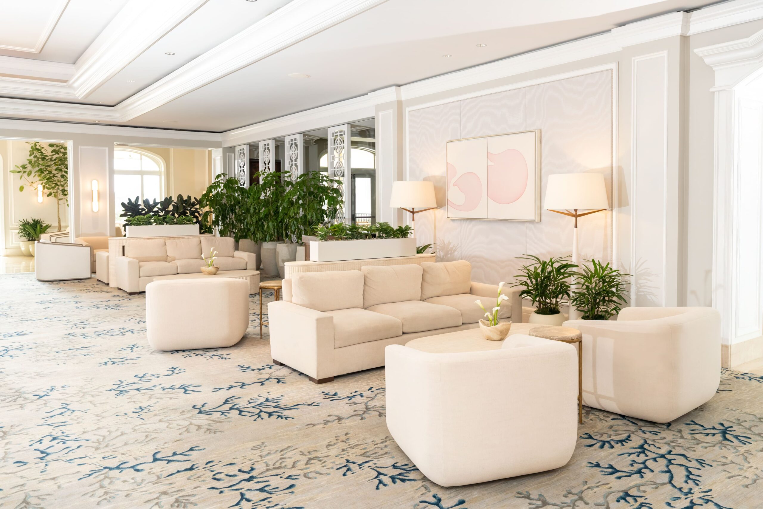 Elegant hotel lounge with cream sofas, lush plants, and soft lighting