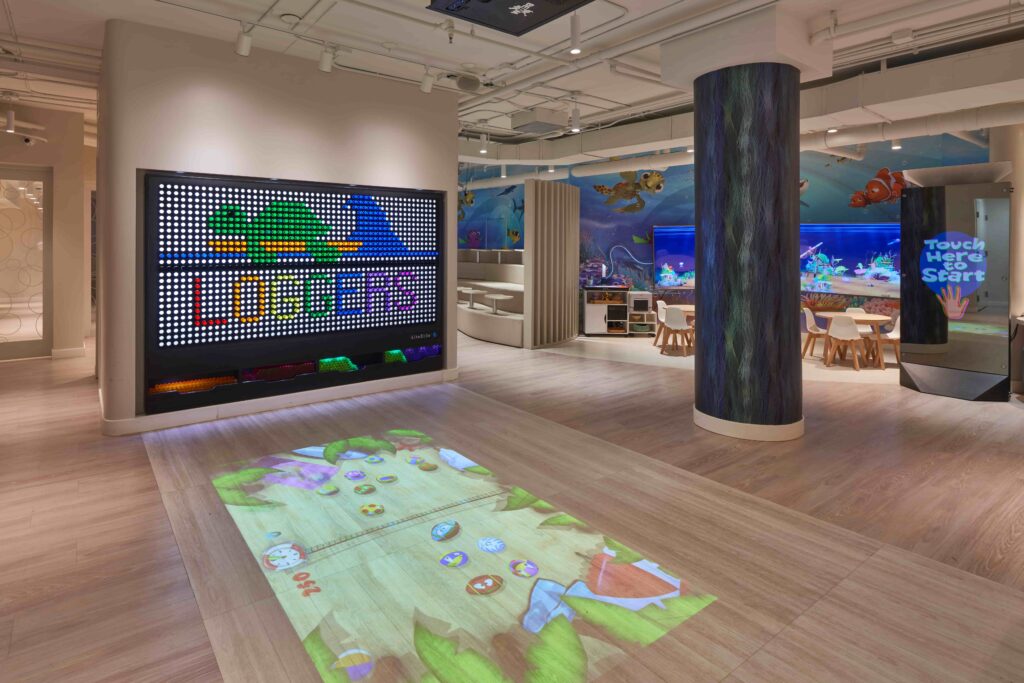 Children’s play area with led wall display, interactive floor game, aquarium tank, and ocean-themed decor
