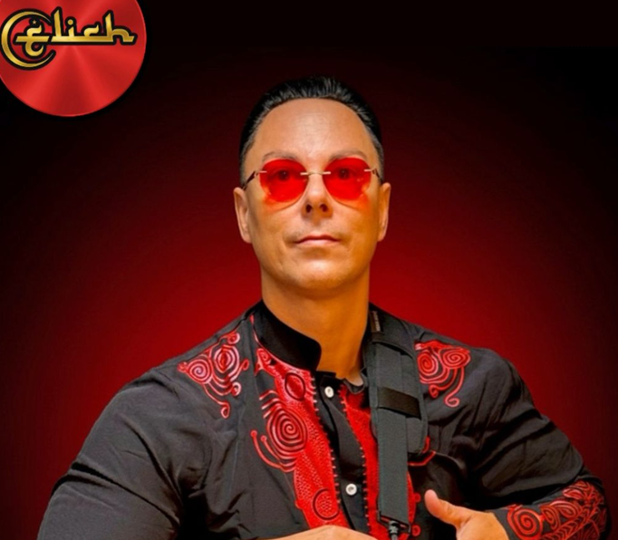 Elich Garcia holding a drum in red‑lit studio.