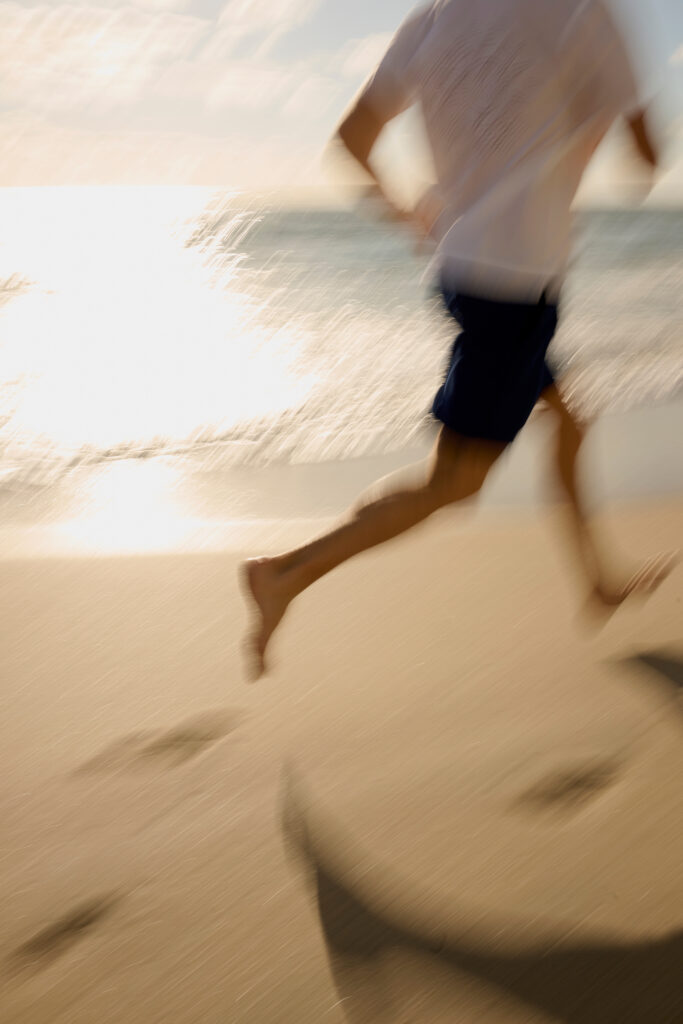 Blurred motion of person running along sunny beach shoreline