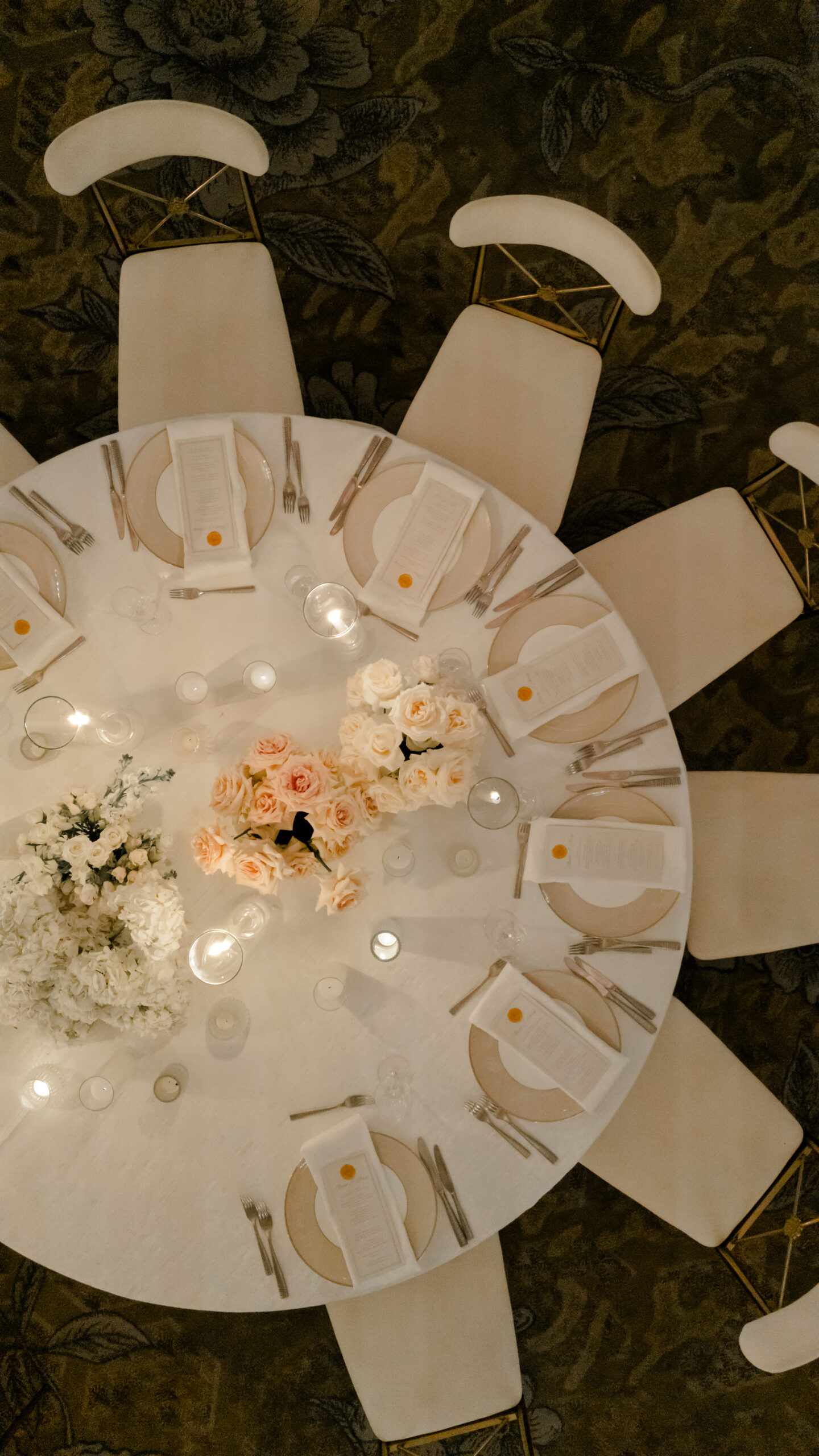 Overhead view of elegant round dining table set with roses, candles, and place settings