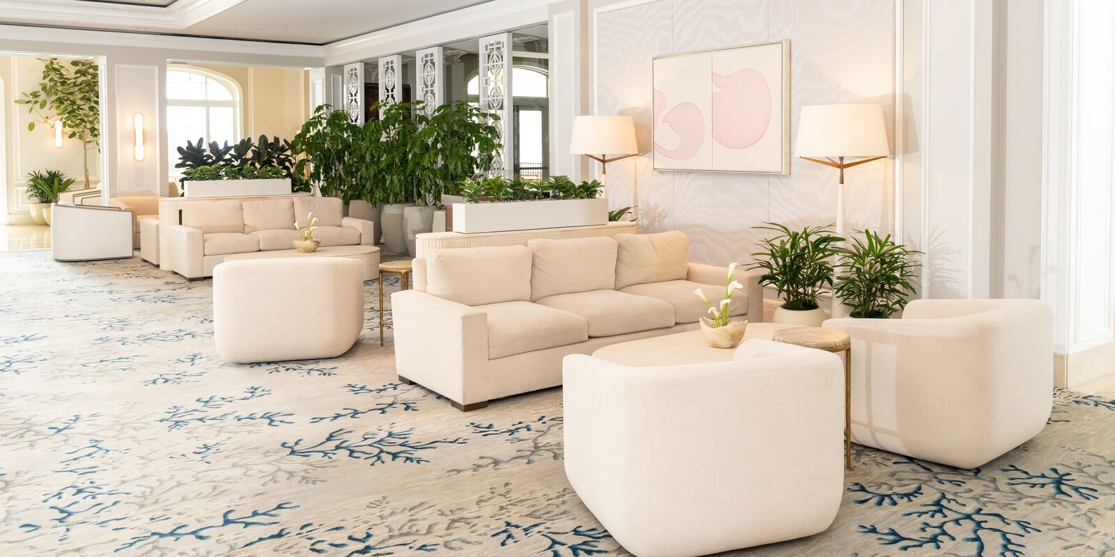 Elegant lounge with plush cream seating, soft lighting and coastal touches creating a calm, welcoming atmosphere