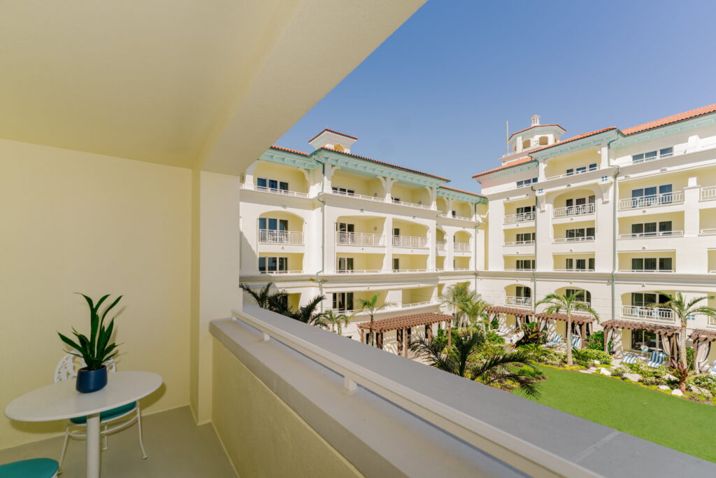 Balcony view of luxury resort courtyard with palm trees and white mediterranean-style buildings