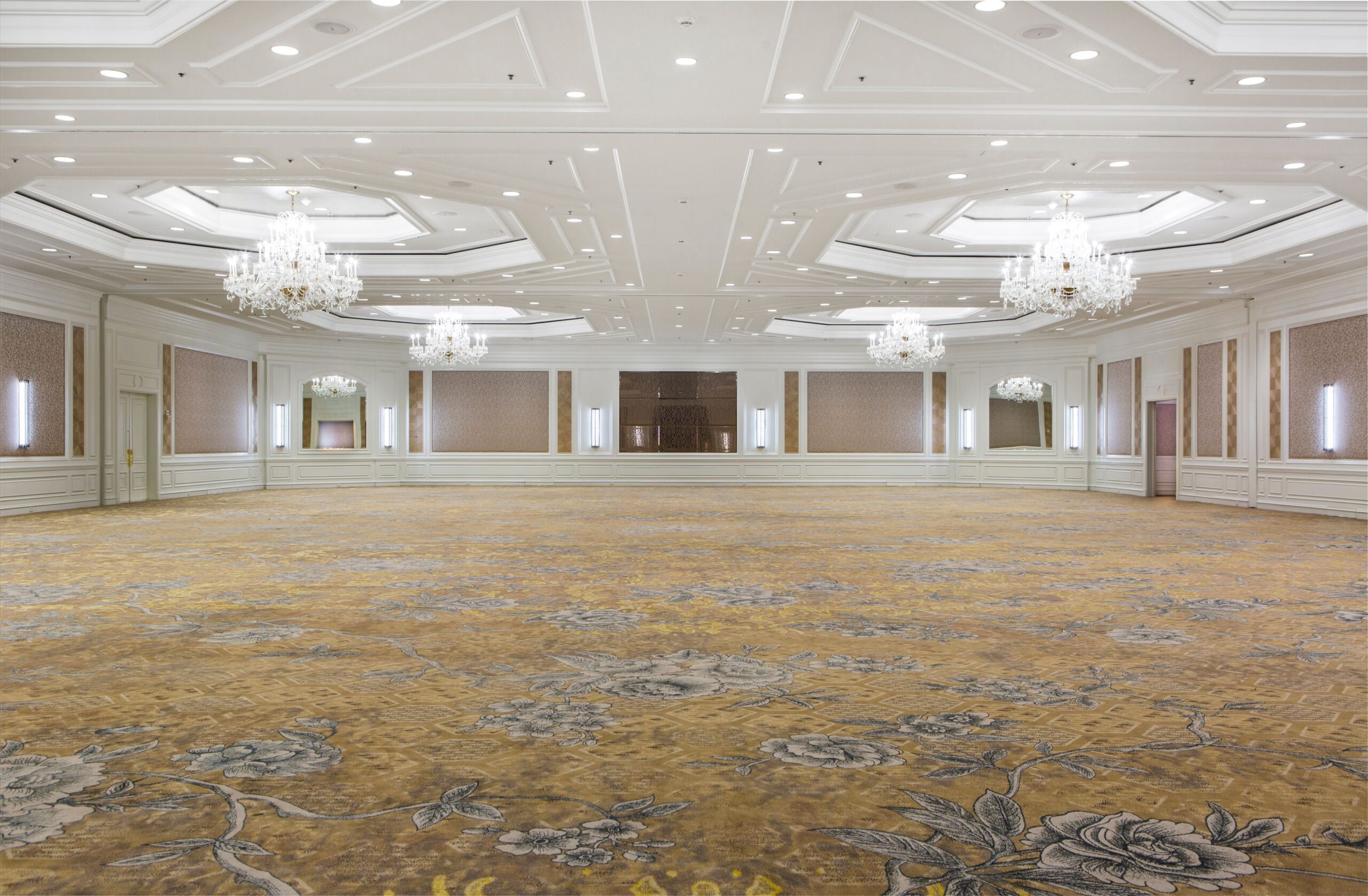 Spacious elegant ballroom with chandeliers, ornate ceiling, and patterned carpet